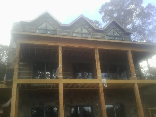 Dormers and porch framing on a large log home under construction — Roof Coating work by our crew in Nordman