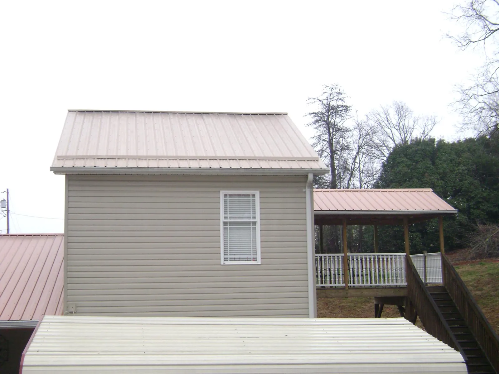 Tan metal roofs on a two story addition and attached porch, from a Roof Replacement job in Nordman
