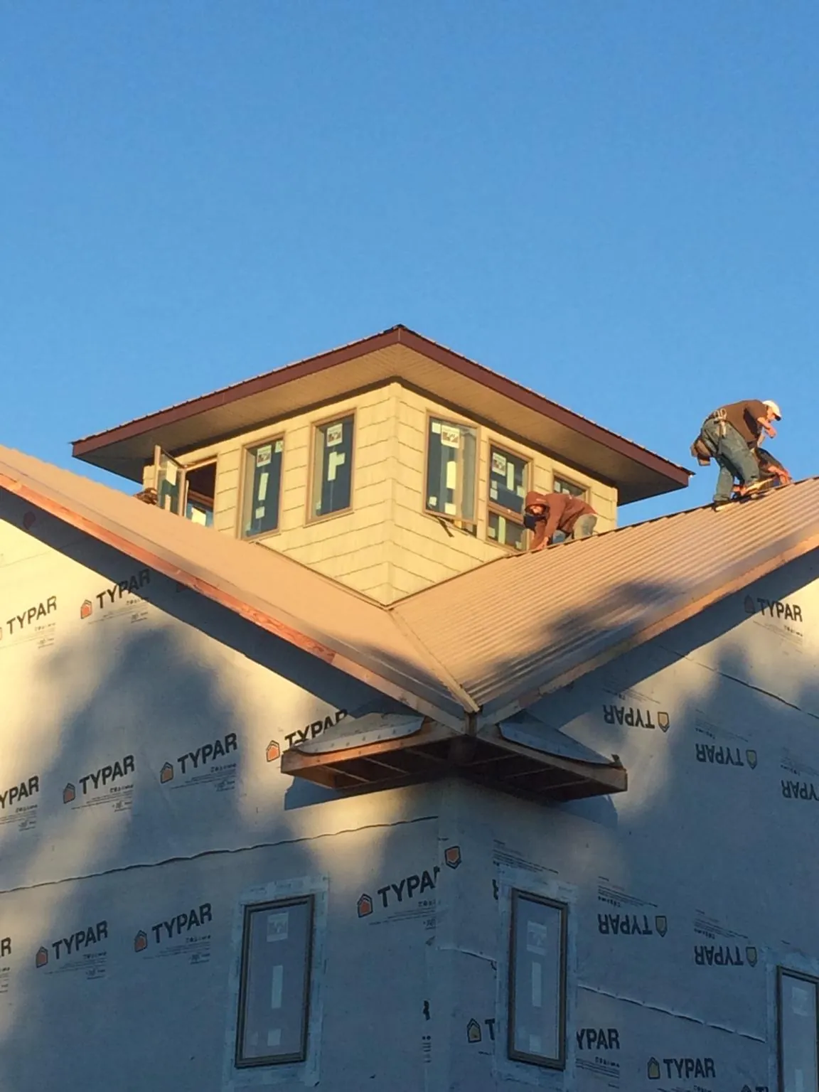 Roofers working around a rooftop cupola on a new metal roof at sunset — Roof Waterproofing in Nordman by Roofing Brothers